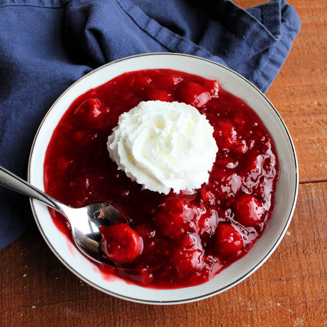 This fun cherry pineapple "salad" is sure to be a hit with your family. It is a simple make ahead side dish or simple dessert that is festive for a holiday or fun for a BBQ. serving of cherry pineapple jello topped with whipped cream