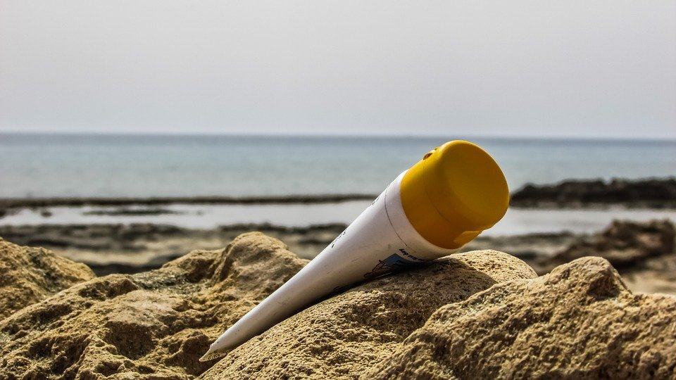 A tube of sunscreen lying in the sand on the beach