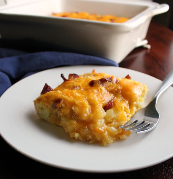 This easy breakfast casserole is made quickly with the help of tater tots. The eggs, cheese and ham or bacon round it out for a delicious and filling start to your day. piece of ham and cheese tater tot breakfast casserole ready to eat