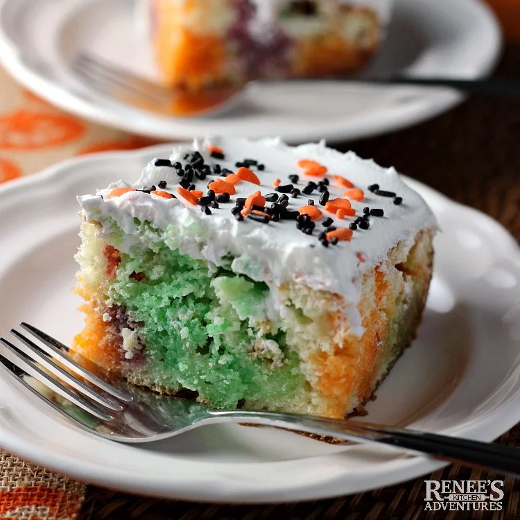 Two pieces of Halloween Jello Poke Cake by Renee's Kitchen Adventures on white plates one in the front and one in the back