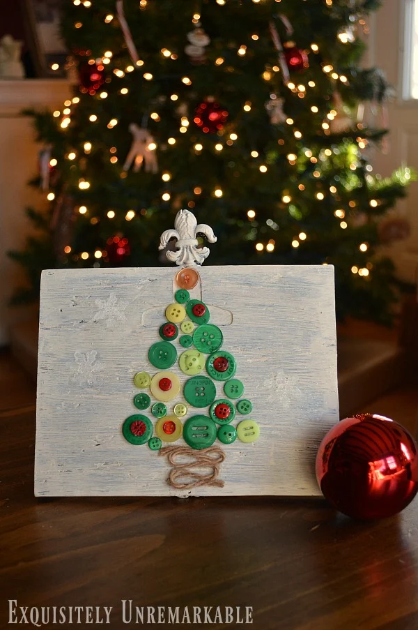 Button Christmas Tree mounted on wooden frame and twine stem on table in front of Christmas tree