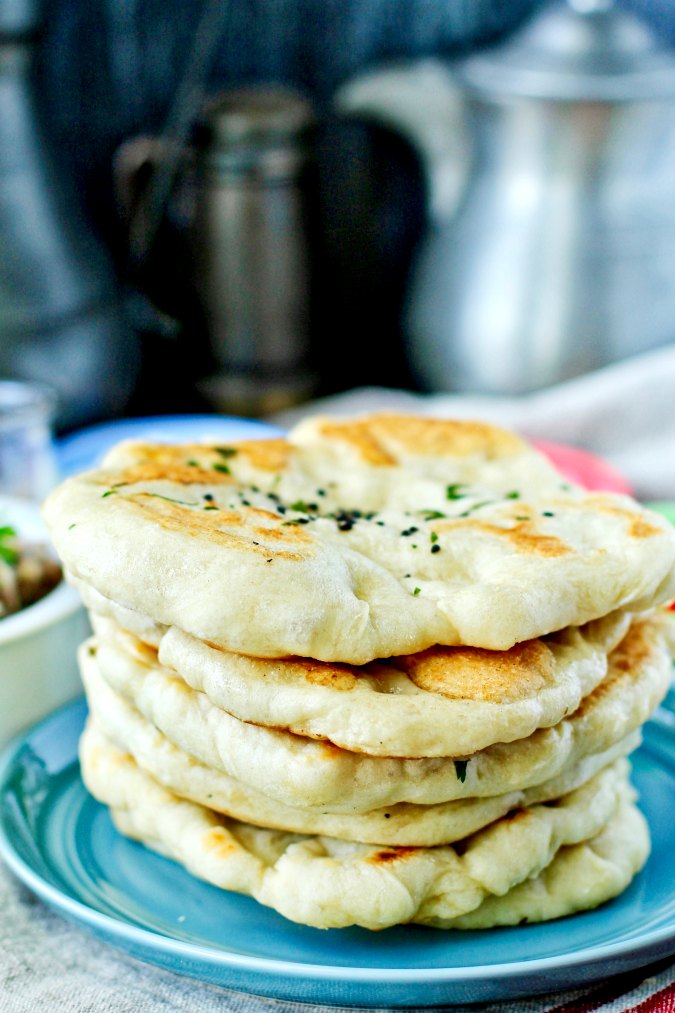 Kulcha stacked on a blue plate.