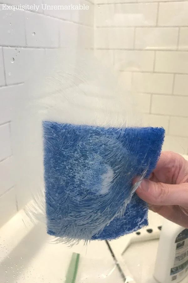 Cleaning shower doors with a blue scotch brite pad