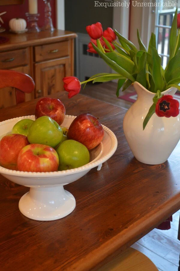 Apples in a white pedestal bowl on a table