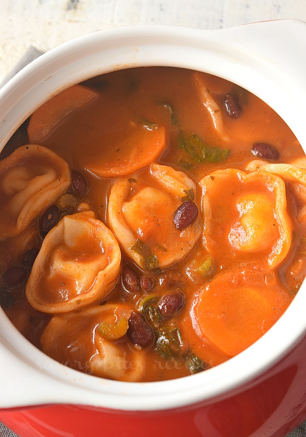 a white pot with minestrone with tortellini soup