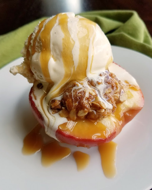 The perfect individual sized dessert, these mini apple crisp baked apples are the perfect mix of baked apples and crisp topping. Serve it with a scoop of ice cream for a perfect dessert! apple half baked with crisp topping inside and topped with a scoop of ice cream and drizzle of caramel