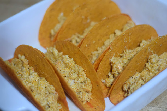 The buffalo chicken filling added to the taco shells in the baking dish. 