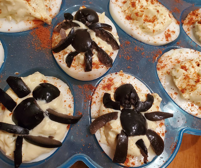 these are deviled eggs with spiders on them made out of black olives