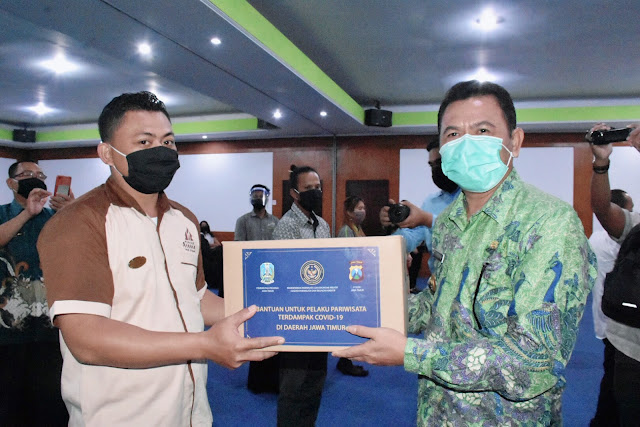 Mojokerto - Kementerian Pariwisata dan Ekonomi Kreatif (Kemenpar) Republik Indonesia, menyerahkan 398 paket bantuan sembako pada para pelaku usaha yang terdampak Covid-19 di Kabupaten Mojokerto. Mereka adalah 217 orang pelaku usaha hotel, 19 orang pelaku usaha rumah makan/restoran/cafe, 47 orang pelaku usaha rekreasi, 3 orang pelaku usaha travel, 13 pelaku usaha kebugaran, 81 pelaku usaha kios PKL di lokasi wisata, dan 18 orang perajin souvenir.  Bantuan diserahkan secara simbolis kepada 40 orang perwakilan, oleh Bupati Mojokerto Pungkasiadi, didampingi Wakapolres Mojokerto Kompol David Triyo Prasojo, Selasa (2/6/2020) pagi di Hotel Grand Whiz Trawas.  Bupati Pungkasiadi pada arahannya menyampaikan, saat ini Pemerintah Kabupaten Mojokerto masih menunggu instruksi pusat terkait pembukaan kembali tempat pariwisata jika new normal telah diterapkan. Masalah Covid-19 belum dapat dipastikan kapan selesainya, sehingga pusat dan daerah harus paralel bangkit bersama menciptakan iklim kondusif.  Rencana pelaksanaan new normal pun akan sangat membutuhkan koordinasi, kolaborasi, dan kerjasama antara pemerintah dan stakeholder. Untuk memacu berbagai pemikiran dan kreatifitas pemerintah daerah, maka Kementrian Dalam Negeri (Kemendagri) akan melaksanakan Lomba Inovasi Tatanan Normal Baru Produktif dan Aman Covid-19. Ada tujuh sektor yang akan dinilai, yakni pasar tradisional (pasar tradisional C-9), pasar modern (mall, minimarket atau pasar modern C-19), restoran (restoran C-19), hotel (hotel C-19), PTSP (PTSP C-19), tempat wisata (tempat wisata C-19), dan transportasi umum (transportasi umum C-19).  “Kapan pariwisata bisa dibuka, kita tunggu instruksi dari pusat. Atau kita dapat membuka lebih dulu, namun dengan memperhatikan protokol kesehatan yang maksimal disertai dengan inovasi-inovasi. Kita berharap agar new normal ini, bisa menjadi cara agar kita tetap hidup produktif. Namun, kita tidak akan berhenti berusaha mencegah persebaran Covid-19,” ujar Bupati Pungkasiadi.  Senada dengan bupati, Wakapolres Mojokerto Kompol David Triyo Prasojo pada sambutanntya menegaskan jika kedisiplinan adalah kunci utama penerapan new normal. Kedisiplinan tersebut, tentunya harus dibarengi dengan penerapan protokol kesehatan dengan baik.  “Disiplin sangat dibutuhkan dalam penerapan new normal. Semua aturan dan protokol kesehatan harus dipatuhi. Budaya masyarakat kita pun adalah gotong royong, dengan itu semua kita bisa bersama-sama berperan memotong rantai persebaran Covid-19,” terang Wakapolres Mojokerto.  Kepala Dinas Pariwisata dan Olahraga Kabupaten Mojokerto Amat Susilo, mengatakan saat ini Pemkab sedang mendata penerima bantuan dari kalangan pelaku usaha.  “Kita data terus bantuan bagi para pelaku usaha yang terdampak Covid-19. Hari ini juga ada 154 paket bantuan dari Provinsi Jawa Timur, bagi teman-teman seniman dan budayawan di Kabupaten Mojokerto. Pemerintah sedang mempersiapkan tatanan new normal, yang beberapa hari ini akan dilakukan dengan membuka tempat pariwisata. Namun sebelum itu, kita atur dulu protokol kesehatan agar bisa diterapkan dengan baik. Kita tunggu kebijakan pemerintah untuk penerapan new normal,” kata Amat. (Jayak)