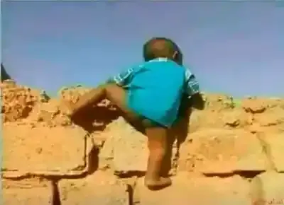 طفل يتسلق سوراً بدون بنطلون ومؤخرته ظاهرة