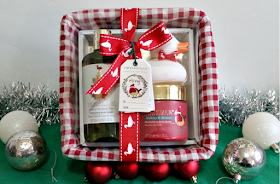a gift basket containing bottles surrounded by tinsel and red and silver baubles