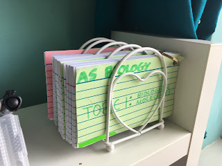 A cream toast rack with a heart on the front, holding four booklets of cue cards.