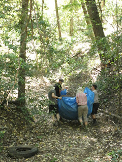 Four teammates hauling a tarp loaded with junk up the trail, Castle Rock State Park, Los Gatos, California
