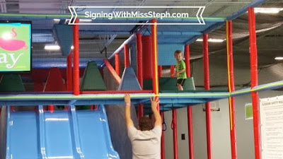 Child running on bridge in 2-story play structure with triple wide slide