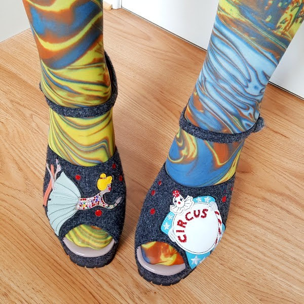 wearing open toe shoes with applique circus characters across toes and marbled tights
