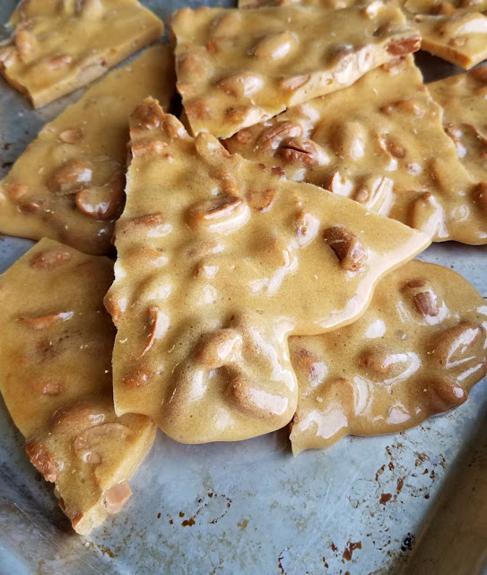 Sweet, crunchy peanut brittle is a classic candy that you can easily make at home. This updated recipe doesn't involve a candy thermometer, just a microwave. Make some asap! shards of microwave peanut brittle on baking sheet