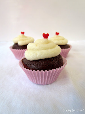 Brownie Bites with white frosting on top and a heart sprinkle on white background 