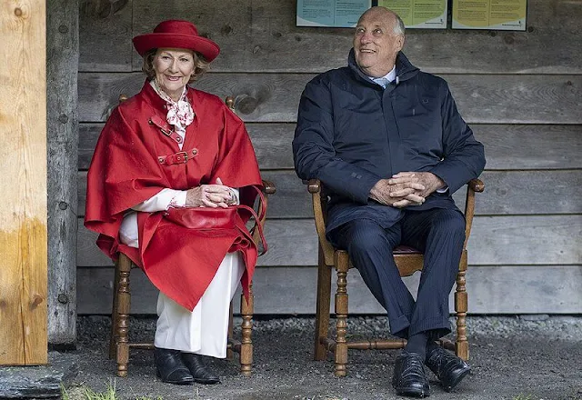 Queen Sonja wore a red wool cashmere cape coat, and white trousers