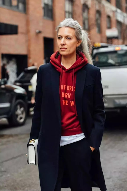 A woman wear a black coat and red hoodie