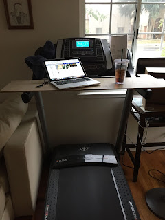 treadmill with board desk containing laptop and drink