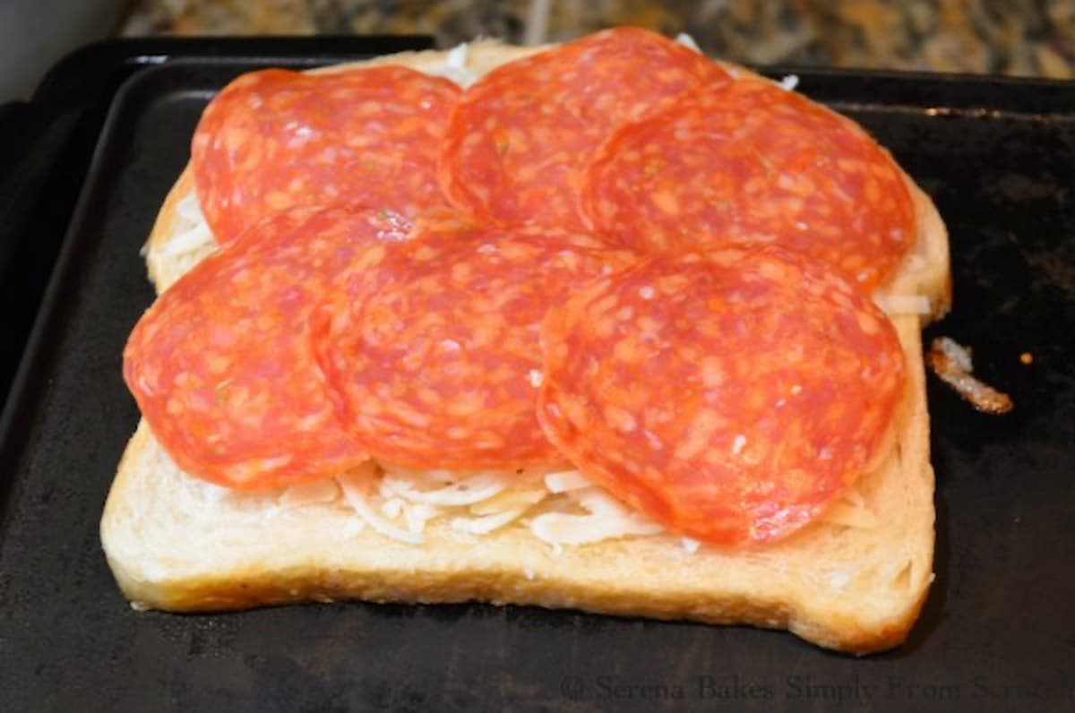 6 slices of pepperoni on top of cheese on sourdough bread layering to make Pepperoni Pizza Grilled Cheese Sandwich.