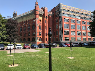 The Drying Green – opposite the Templeton Building.  The photo shows an area of lawn with black clothes poles in it and a short distance behind these is the large and ornate, red brick building of the old Templeton's Carpet Factory.  Photo by Kevin Nosferatu for The Skulferatu Project.