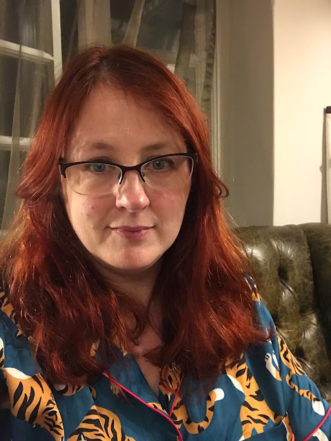 A redheaded woman in teal pyjamas with tigers printed on them