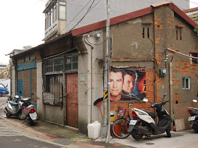 Portion of Broken Arrow movie poster with John Travolta and Christian Slater on a building's wall