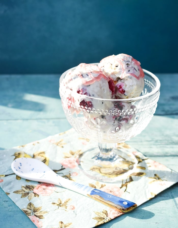Raspberry ripple ice cream in a sundae glass with white ceramic spoon