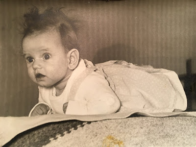 black and white photograph of Corina Duyn as 2 month old baby, lying on her belly, hair in a mess