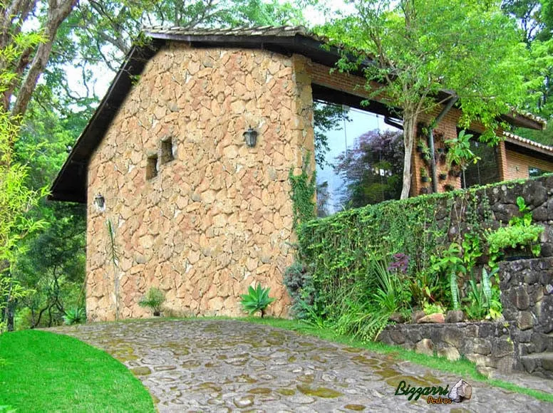Parede de pedra moledo assentada tipo duas faces em construção de residência com os muros de pedra, o calçamento de pedra e a execução do paisagismo.