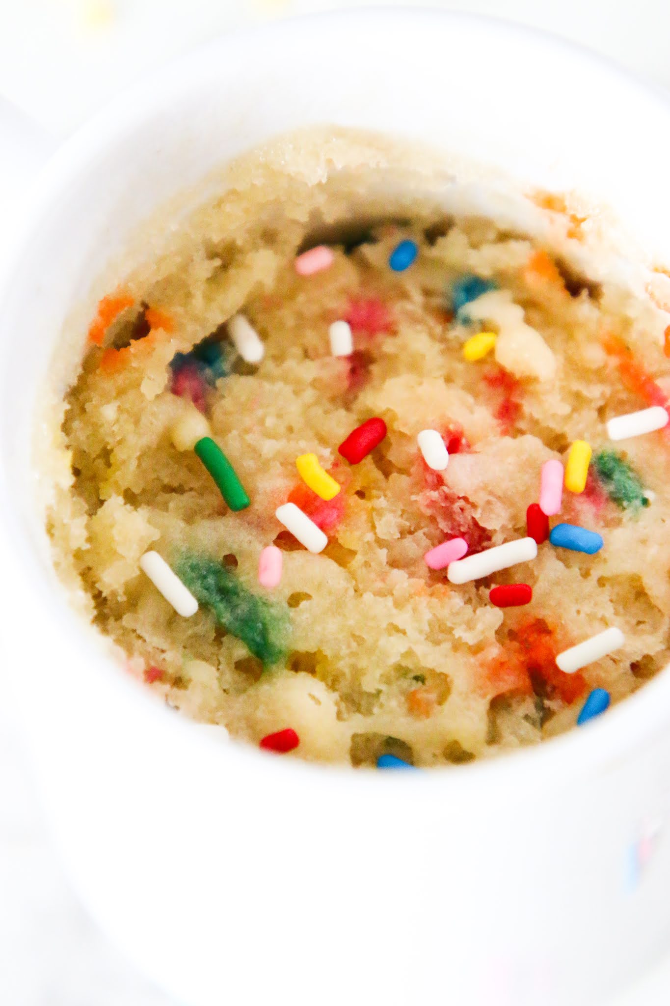confetti cake in a mug with a fork and rainbow sprinkles