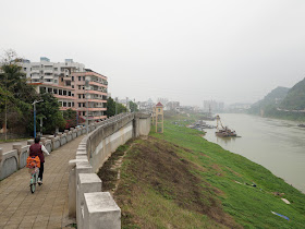 woman riding a bicycle on a wall bordering the Gui River (桂江) in Wuzhou (梧州)