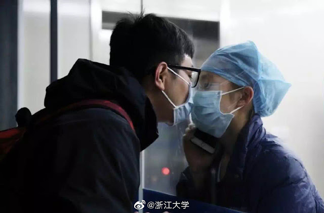 ممرضة صين ة تقبل خطيبها من خلف حاجز زجاجي