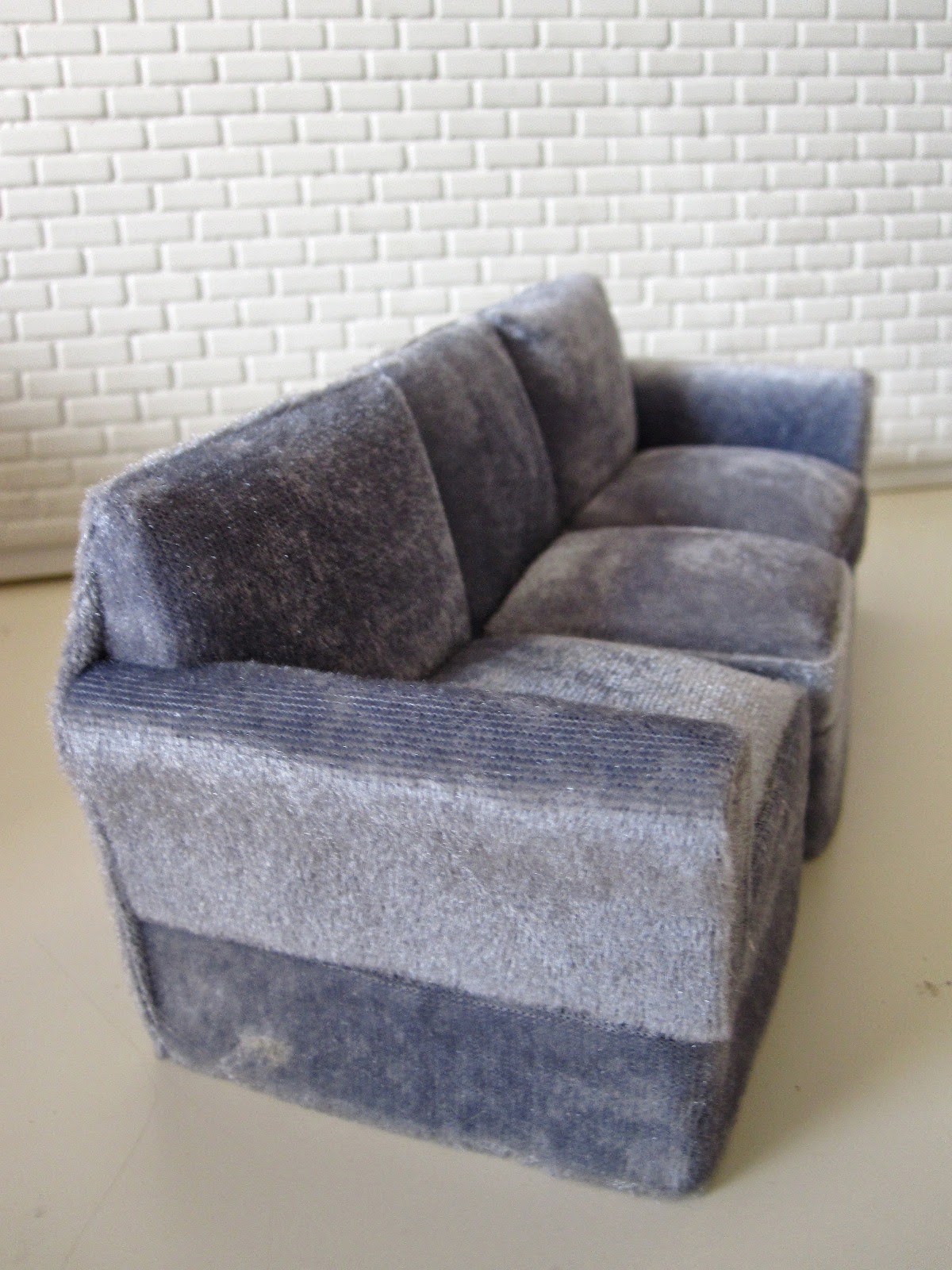 Modern miniature three seater grey velvet sofa.