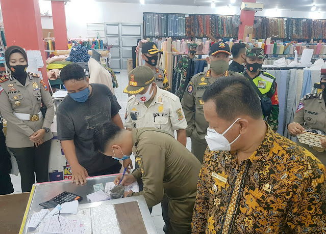 Manejemen Sultan Keraton Mojopahit Dikenakan Denda 200 Ribu Mojokerto - Wakil Wali Kota Mojokerto, Achmad Rizal Zakaria bersama Polresta Mojokerto, Satpol PP Kota Mojokerto serta Gugus Tugas Covid-19 Kota Mojokerto melaksanakan penegakan disiplin dan Penegakan hukum Inpres no 6 tahun 2020 dengan Sasaran Sanrio, Superindo dan Sultan Keraton Mojopahit, Kamis (3/9/2020). Kapolresta Mojokerto AKBP Deddy Supriadi SH. MIK mengatakan jika harus ada petugas yang mengelilingi dalam swalayan untuk mengingatkan pengunjung yang tidak memakai masker, berkerumun ataupun yang melanggar petunjuk arah keluar, masuk atau searah. "Di keraton ini, saya lihat tabung cuci tangannya terlalu kecil, harus diganti yang 50 liter. Seminggu lagi kami cek. Jika pihak manejemen Keraton masih melanggar lagi, akan kami kenakan denda lebih besar lagi. Jadi pihak manejemen Keraton tadi wajib membayar pajak 200 ribu. Karena di dalam Keraton Mojopahit tidak ada petunjuk arah keluar masuk maupun searah. Selain itu tidak ada petugas yang berkeliling dalam swalayan untuk mengingatkan pengunjung agar selalu tetap pakai masker dan tidak berkerumun. Jadi Pak Agus tadi selaku perwakilan manejemen Keraton langsung mengisi BAP dan membayar di depan, karena ada mobil Bapenda di depan Keraton ini tadi. Setelah membayar, baru bisa ambil KTP di Satpol PP," tandasnya. Sementara itu, Wakil Walikota Mojokerto, Achmad Rizal Zakaria atau yang akrab disapa Cak Rizal mengatakan jika petunjuk arah masuk dan keluar itu untuk jalan yang besar. Kalau terlalu sempit jalannya ya kasih petunjuk jika itu jalannya hanya satu arah. "Biar ada perbedaannya, sebelum dan sesudah covid itu. Biar pengunjung mengikuti petunjuk arah yang ada di Swalayan di Kota Mojokerto. Terkait alasan kami memberikan denda 200 ribu pada pihak manejemen Sultan Keraton Mojopahit itu agar Pihak manejemen jera dan benar-benar disiplin dan mematuhi protokol kesehatan Covid-19," pungkasnya.(Tik)