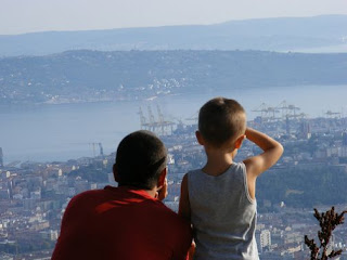 [uomo con un figlio maschio che guardano la citta: natura, paesaggio, mare, montagne, colline e cielo]