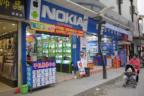 Store with large Nokia sign also showing signs for Apple, Android, and Samsung