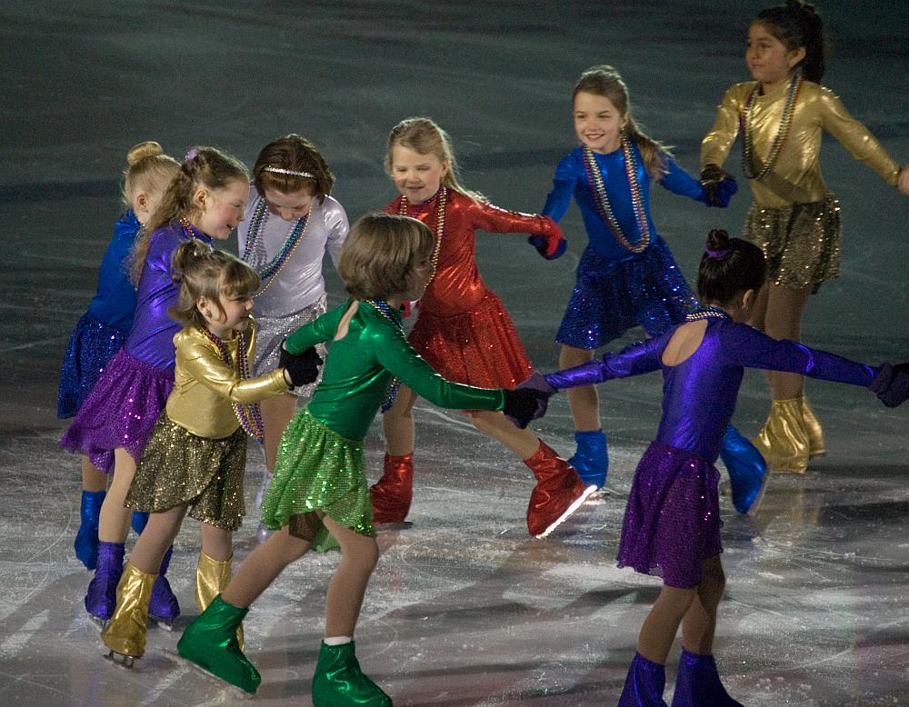 A group of young girls in costume at a figure skating event.