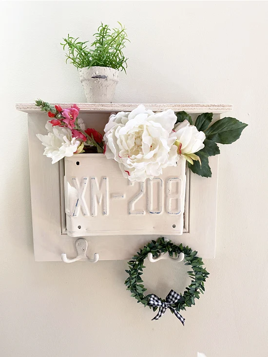 white shelf with plant and wreath filled with flowers