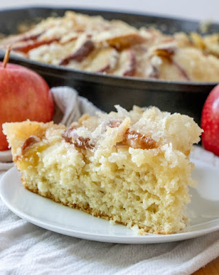 This dutch apple cake recipe has been in my family for generations. It is a simple cake topped with apples and plenty of golden topping. It is great as a coffee cake at breakfast, for an afternoon treat or as a simple dessert. You can take it straight from my great-great grandma's recipe box and put it into yours! Looking across a slice of dutch apple cake, showing the cake layer with apples on top, remaining cake in background