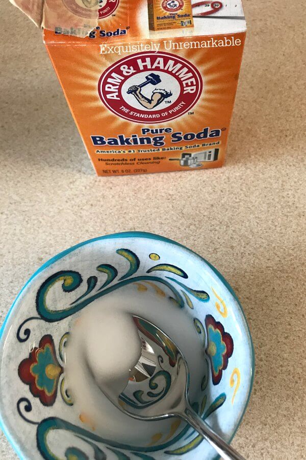 Baking Soda box and baking soda paste mixture in a bowl with a spoon