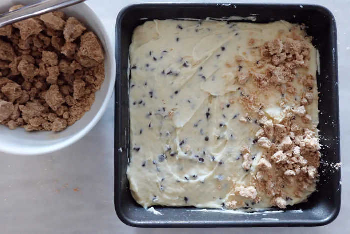 adding crumb topping to cake batter in pan