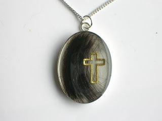 Sterling silver pendant with a lock of hair and cross symbol