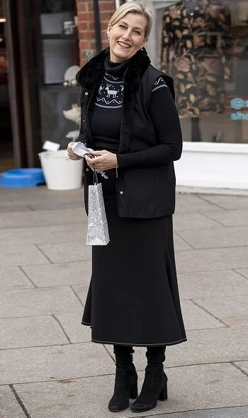 The Countess of Wessex wore a black reindeer-patterned jumper, gilet, and chic long skirt. Patrick Mavros pangolin earrings in sterling silver