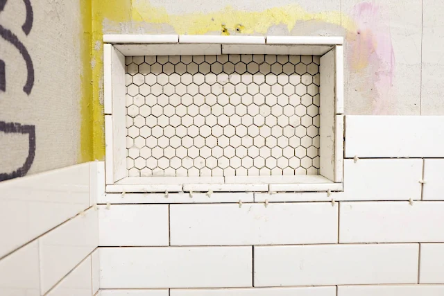 tiling around shower niche with cut subway tiles