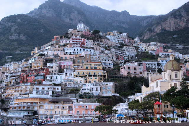 Pastel-coloured houses of a village perched into a mountain range.