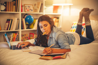 Teenager does her homework in her bedroom