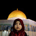 A Palestinian girl prays in front of the Dome of the Rock