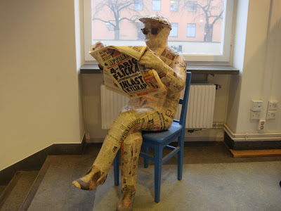 Sculpture of man reading newspaper, made from newspapers
